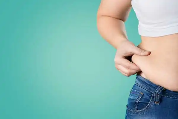 Image of woman pinching her love handles to show weight gain Midlands